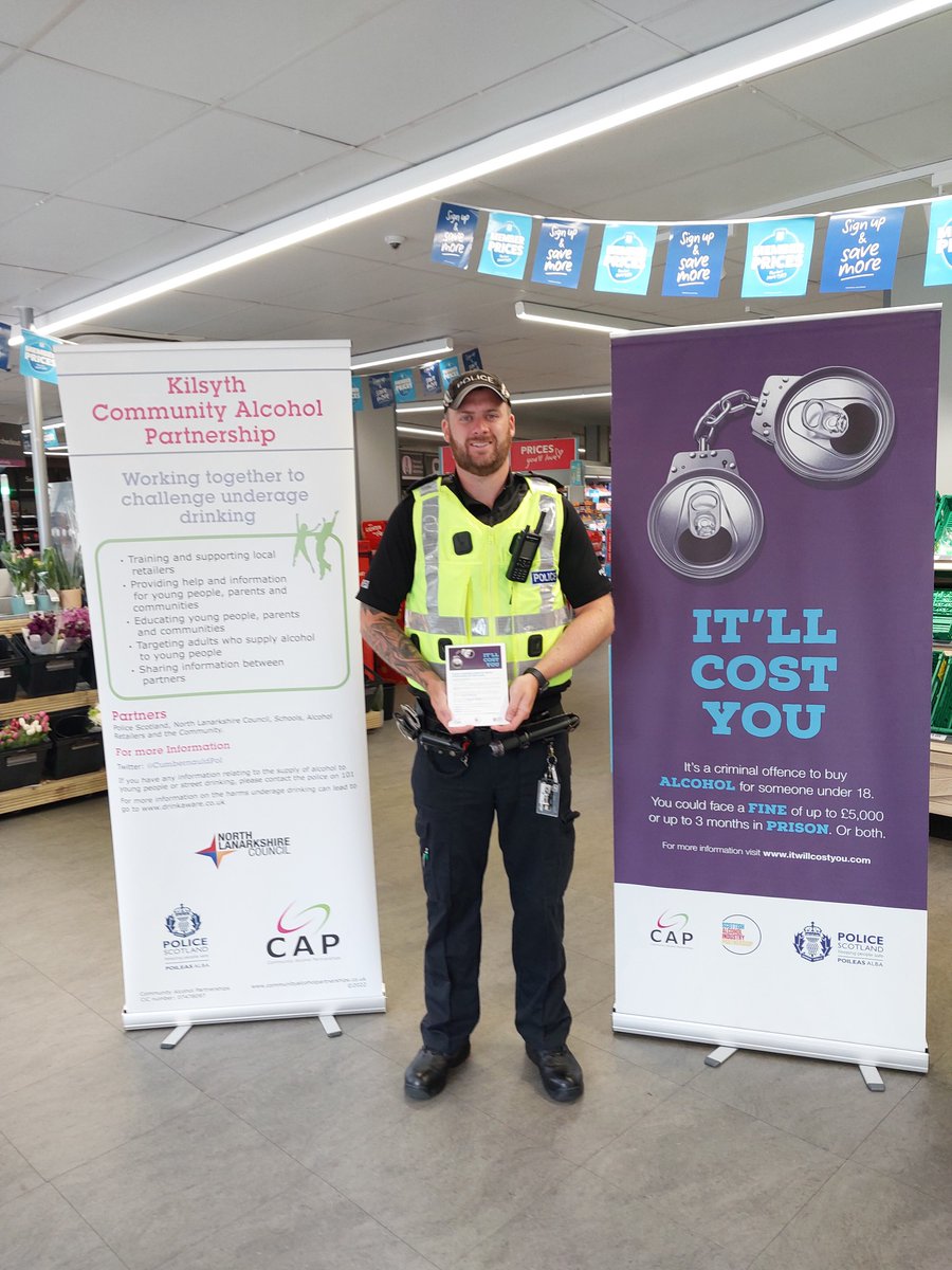 Police officer with two pop up banners with information about it will cost you and community alcohol partnership.
